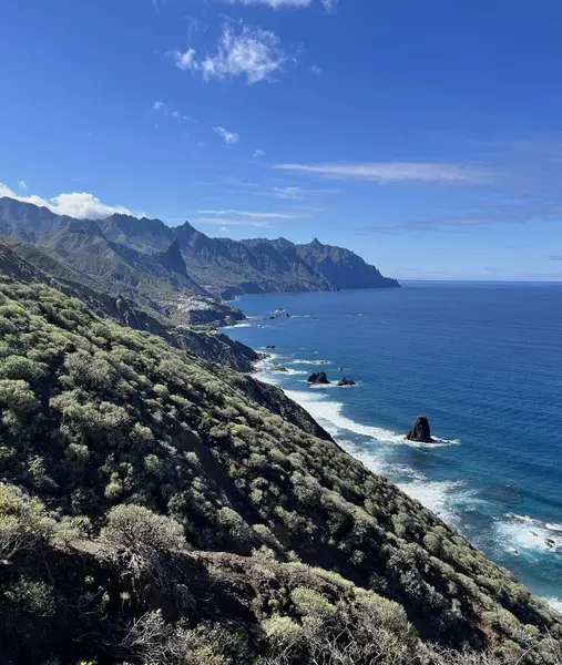İspanya 'nın kuzeyindeki Tenerife, Kanarya Adaları' ndaki engebeli uçurumların ve Atlantik Okyanusu kıyılarının manzarası. Açık mavi gökyüzü ve deniz manzaralı dramatik volkanik manzara.