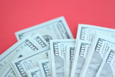 Büyük miktarlarda 100 dolarlık banknotlar parlak kırmızı kağıtların üzerinde duruyor.