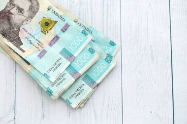 Beyaz ahşap masa üzerinde modern tasarımı olan büyük miktarda Ukrayna yapımı 100 Hryvnia para faturası. Finansal konsept, iş ücretleri