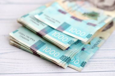 Beyaz ahşap masa üzerinde modern tasarımı olan büyük miktarda Ukrayna yapımı 100 Hryvnia para faturası. Finansal konsept, iş ücretleri