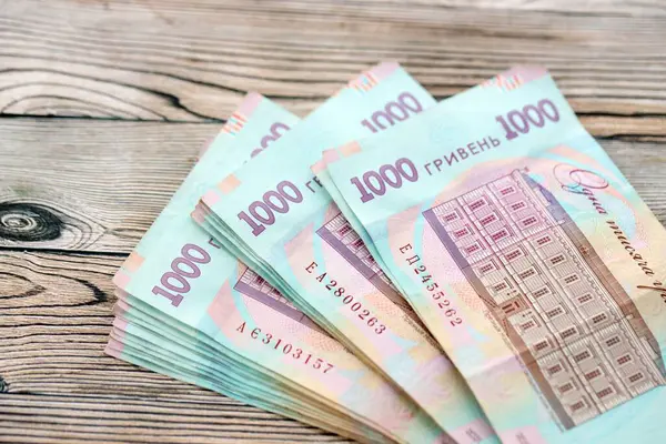 Ahşap arka planda modern tasarımı olan büyük miktarda Ukrayna yapımı 100 Hryvnia para faturası. Finansal konsept, iş ücretleri