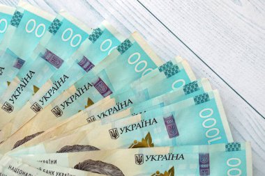 Beyaz ahşap masa üzerinde modern tasarımı olan büyük miktarda Ukrayna yapımı 100 Hryvnia para faturası. Finansal konsept, iş ücretleri