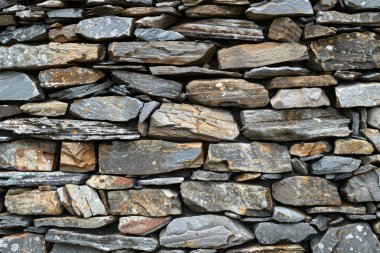 Eski gri ve kahverengi uzun taş duvarın fotoğrafı. Arkaplan veya haritalama için arkaplan dokusu