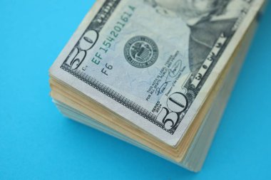 Büyük miktarda 50 dolarlık banknotlar parlak mavi renkli kağıtların üzerinde uzanır.
