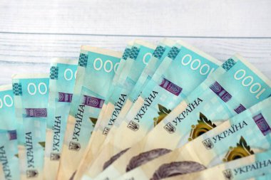 Beyaz ahşap masa üzerinde modern tasarımı olan büyük miktarda Ukrayna yapımı 100 Hryvnia para faturası. Finansal konsept, iş ücretleri
