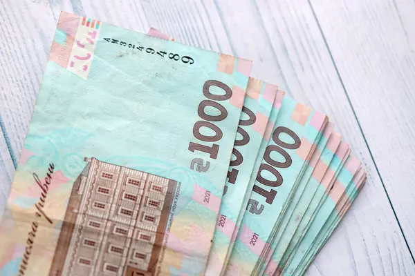 Beyaz ahşap masa üzerinde modern tasarımı olan büyük miktarda Ukrayna yapımı 100 Hryvnia para faturası. Finansal konsept, iş ücretleri