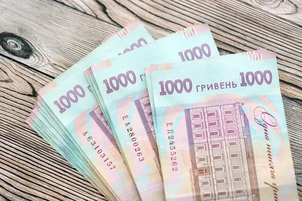Ahşap arka planda modern tasarımı olan büyük miktarda Ukrayna yapımı 100 Hryvnia para faturası. Finansal konsept, iş ücretleri