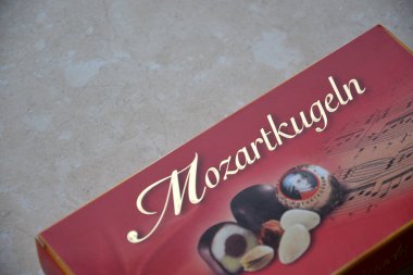 KHARKIV, UKRAINE - 2 Şubat 2024 Kırmızı Mozart Kugeln şekerleri kutusu mermer arka planda yakın plan