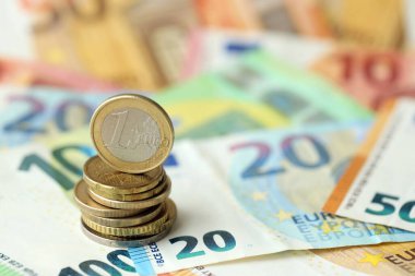 Bir avroluk para, muazzam miktardaki farklı avro banknotlarının üzerinde yatıyor.