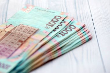 Beyaz ahşap masa üzerinde modern tasarımı olan büyük miktarda Ukrayna yapımı 100 Hryvnia para faturası. Finansal konsept, iş ücretleri
