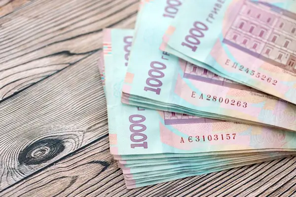 Ahşap arka planda modern tasarımı olan büyük miktarda Ukrayna yapımı 100 Hryvnia para faturası. Finansal konsept, iş ücretleri