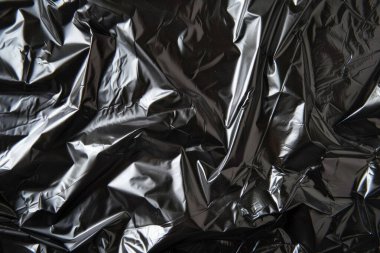 Buruşmuş siyah politen plastik ambalaj kağıdının fotoğrafı. Arkaplan veya haritalama için arkaplan dokusu