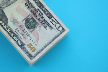Büyük miktarda 50 dolarlık banknotlar parlak mavi renkli kağıtların üzerinde uzanır.