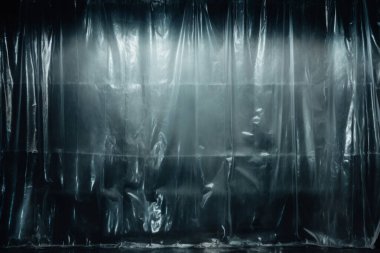 Siyah buruşmuş plastik filmin işlenmiş görüntüsü, koyu bir arkaplanda gölgeler.