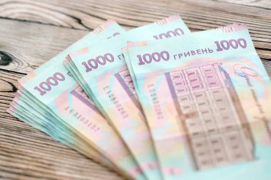 Ahşap arka planda modern tasarımı olan büyük miktarda Ukrayna yapımı 100 Hryvnia para faturası. Finansal konsept, iş ücretleri