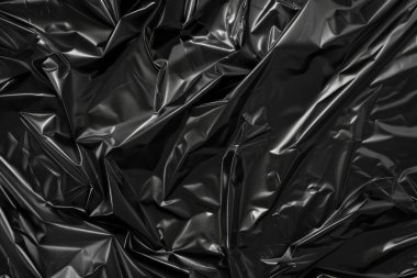 Buruşmuş siyah politen plastik ambalaj kağıdının fotoğrafı. Arkaplan veya haritalama için arkaplan dokusu