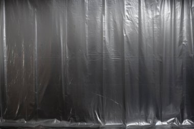 Siyah buruşmuş plastik filmin işlenmiş görüntüsü, koyu bir arkaplanda gölgeler.