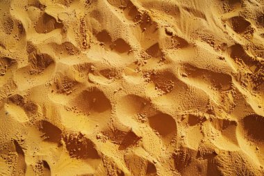 Sahildeki sarı kum yüzeyi fotoğrafı. Yaklaş. Arkaplan veya haritalama için arkaplan dokusu