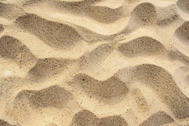 Sahildeki sarı kum yüzeyi fotoğrafı. Yaklaş. Arkaplan veya haritalama için arkaplan dokusu