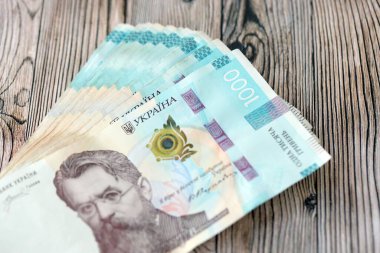Ahşap arka planda modern tasarımı olan büyük miktarda Ukrayna yapımı 100 Hryvnia para faturası. Finansal konsept, iş ücretleri
