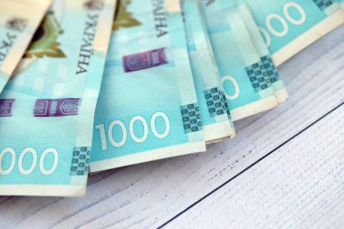 Beyaz ahşap masa üzerinde modern tasarımı olan büyük miktarda Ukrayna yapımı 100 Hryvnia para faturası. Finansal konsept, iş ücretleri