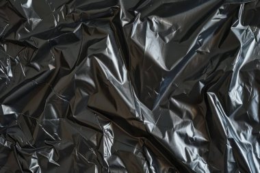 Buruşmuş siyah politen plastik ambalaj kağıdının fotoğrafı. Arkaplan veya haritalama için arkaplan dokusu