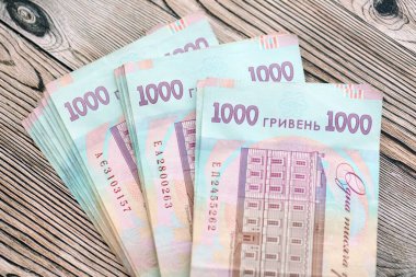 Ahşap arka planda modern tasarımı olan büyük miktarda Ukrayna yapımı 100 Hryvnia para faturası. Finansal konsept, iş ücretleri