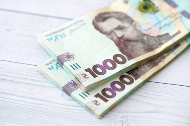 Beyaz ahşap masa üzerinde modern tasarımı olan büyük miktarda Ukrayna yapımı 100 Hryvnia para faturası. Finansal konsept, iş ücretleri