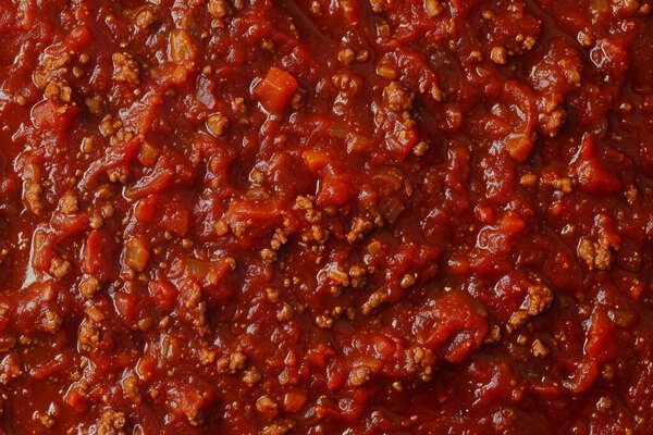 Photo of Dark red bolognese or bolognaise sauce close up. Food photo for backdrops or recipes