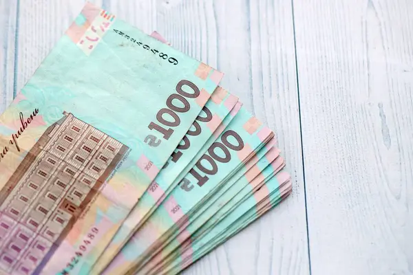 Beyaz ahşap masa üzerinde modern tasarımı olan büyük miktarda Ukrayna yapımı 100 Hryvnia para faturası. Finansal konsept, iş ücretleri