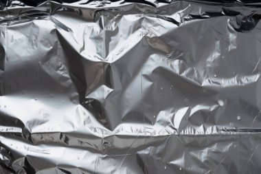 Siyah buruşmuş plastik filmin işlenmiş görüntüsü, koyu bir arkaplanda gölgeler.