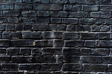 Eski tuğla duvarın resmi siyah renge boyanmış. Yakın plan. Arkaplan veya haritalama için arkaplan dokusu