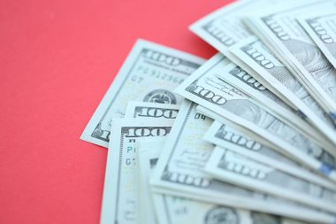 Büyük miktarlarda 100 dolarlık banknotlar parlak kırmızı kağıtların üzerinde duruyor.