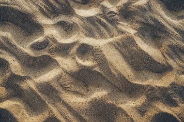 Sahildeki sarı kum yüzeyi fotoğrafı. Yaklaş. Arkaplan veya haritalama için arkaplan dokusu