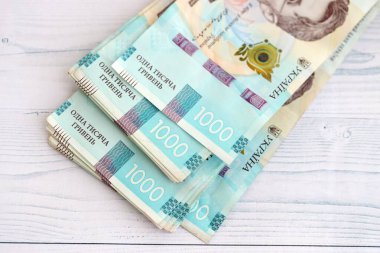 Beyaz ahşap masa üzerinde modern tasarımı olan büyük miktarda Ukrayna yapımı 100 Hryvnia para faturası. Finansal konsept, iş ücretleri