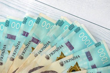 Beyaz ahşap masa üzerinde modern tasarımı olan büyük miktarda Ukrayna yapımı 100 Hryvnia para faturası. Finansal konsept, iş ücretleri