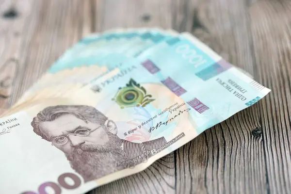 Ahşap arka planda modern tasarımı olan büyük miktarda Ukrayna yapımı 100 Hryvnia para faturası. Finansal konsept, iş ücretleri