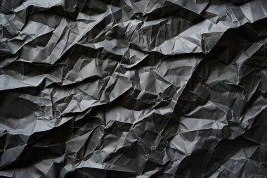 Buruşmuş siyah kâğıt parçalarının fotoğrafı. Arkaplan veya haritalama için arkaplan dokusu