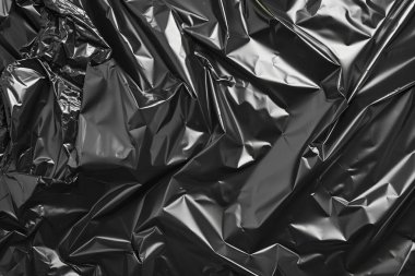 Buruşmuş siyah politen plastik ambalaj kağıdının fotoğrafı. Arkaplan veya haritalama için arkaplan dokusu