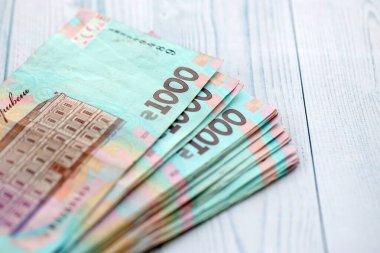 Beyaz ahşap masa üzerinde modern tasarımı olan büyük miktarda Ukrayna yapımı 100 Hryvnia para faturası. Finansal konsept, iş ücretleri