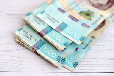 Beyaz ahşap masa üzerinde modern tasarımı olan büyük miktarda Ukrayna yapımı 100 Hryvnia para faturası. Finansal konsept, iş ücretleri