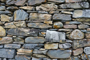 Eski gri ve kahverengi uzun taş duvarın fotoğrafı. Arkaplan veya haritalama için arkaplan dokusu