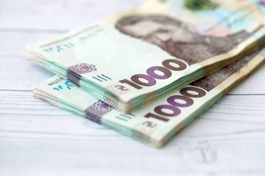 Beyaz ahşap masa üzerinde modern tasarımı olan büyük miktarda Ukrayna yapımı 100 Hryvnia para faturası. Finansal konsept, iş ücretleri