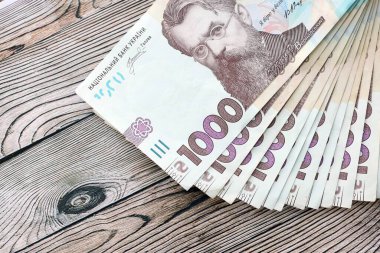 Ahşap arka planda modern tasarımı olan büyük miktarda Ukrayna yapımı 100 Hryvnia para faturası. Finansal konsept, iş ücretleri