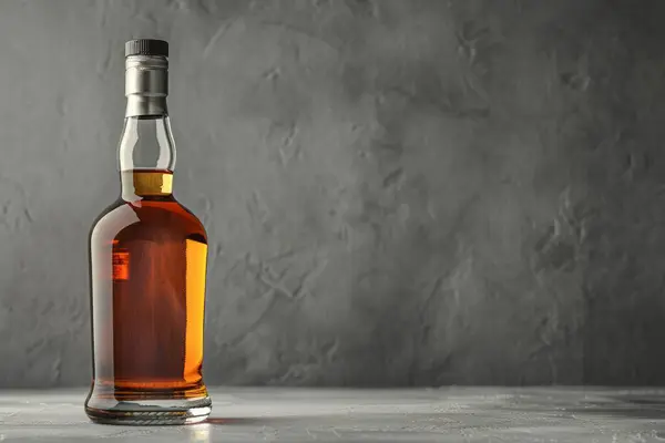 Viski ya da konyak alkol şişesi masanın üzerinde koyu gri arka planda. Profesyonel fotoğraf.