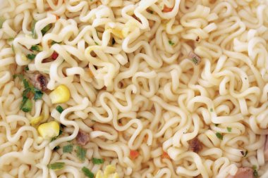 Baharatlı soslu erişte ve doğranmış yeşil soğan parçaları yakın.