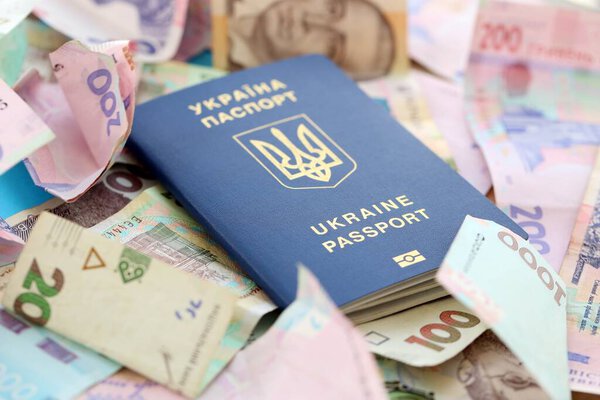 Украинский биометрический паспорт лежит на большом количестве различных украинских гривен денежных счетов крупным планом