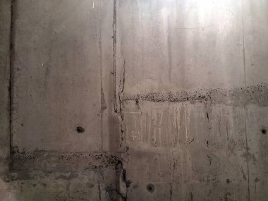 Koyu su ve yağ izlerinin olduğu gri beton duvarın dokusu dikey olarak aşağı iniyor ve birçok iz ve çizgi grundge