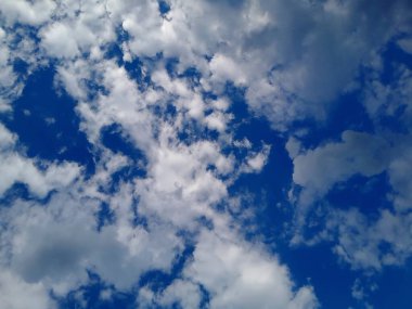 Arkaplanda mavi gökyüzü manzaralı bulutlar var. Mavi gökyüzünde güzel güneşli bulutlar. Güneş kabarık bulutların arasında parlıyor.