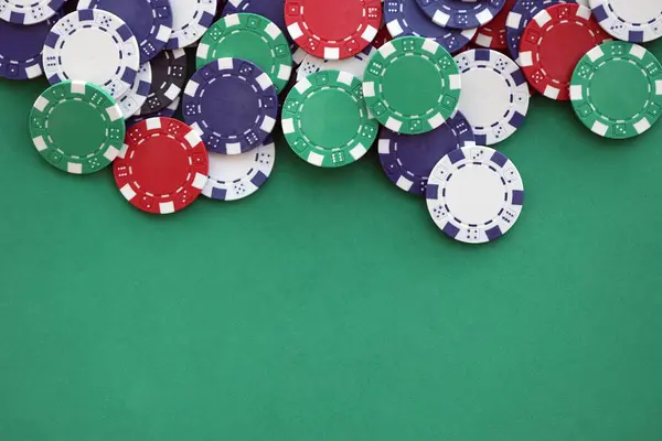 Kumarhane oyun geçmişi, yeşil oyun hasırının üzerine değişik renklerde bahis fişleri yığını. Kapatın.